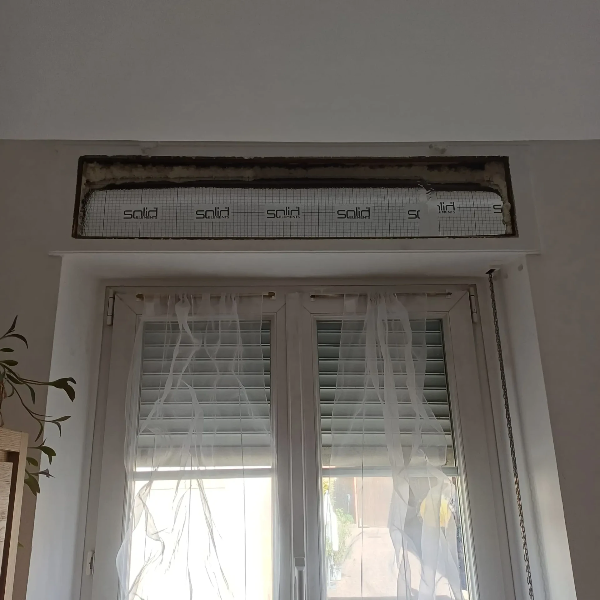 Photo d'intervention Reparrenov : caisson de volet roulant isolé avec panneau isolant à l'intérieur, au-dessus d'une fenêtre
